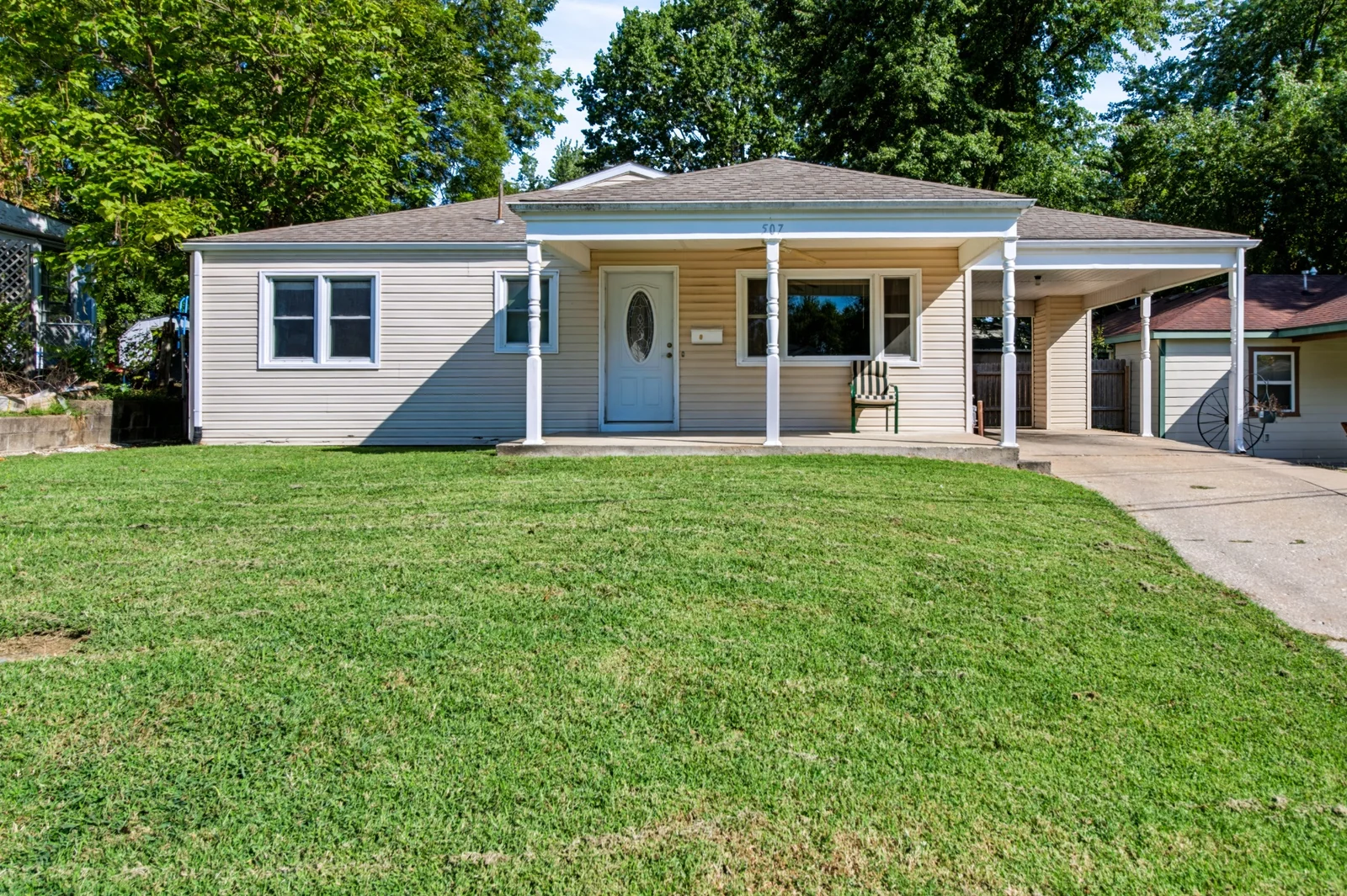 507 Park Ave: beige single-story home with a covered front porch, lawn and attached carport.