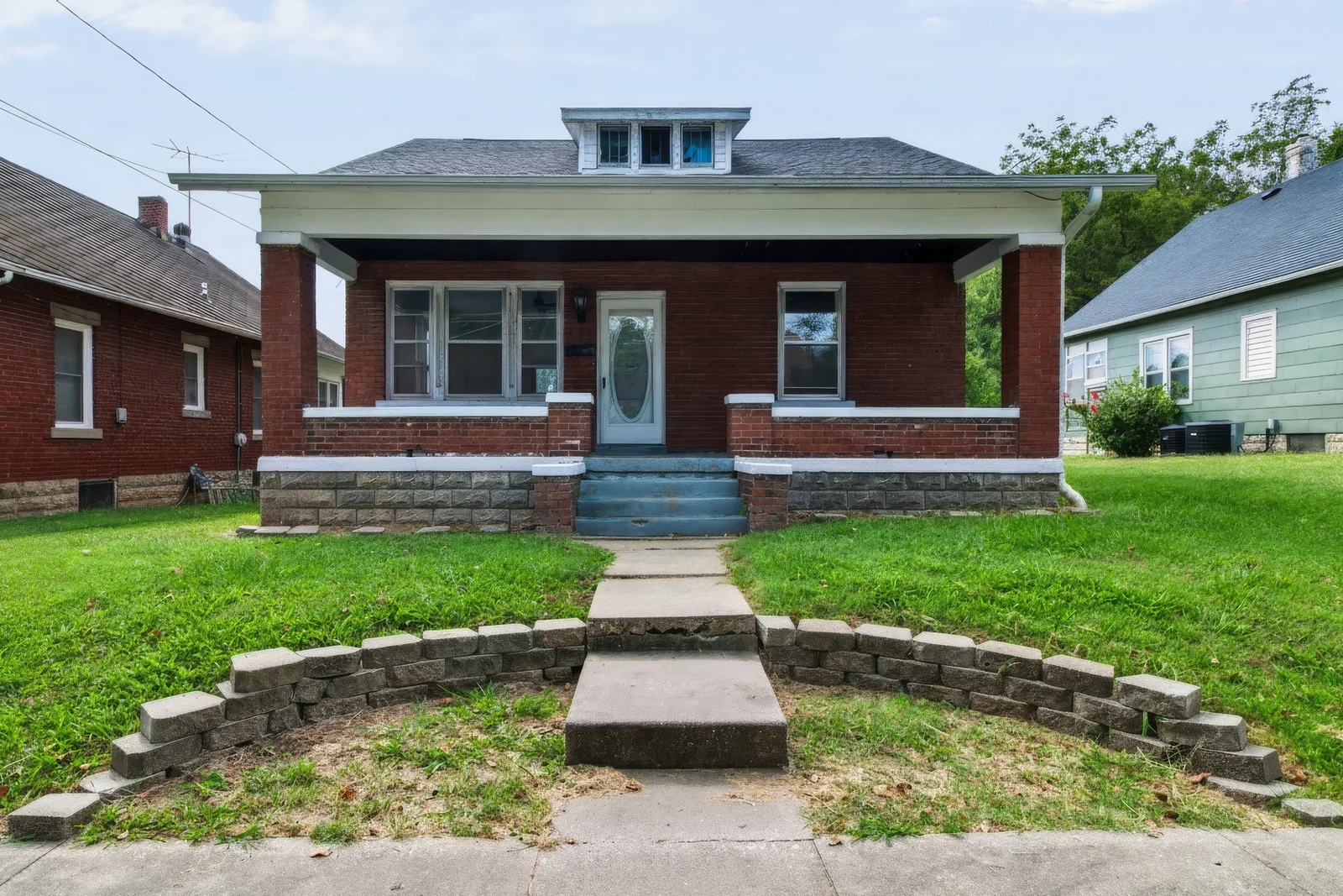 Front exterior of a brick home with a covered porch and central concrete steps at 915 Shamrock.