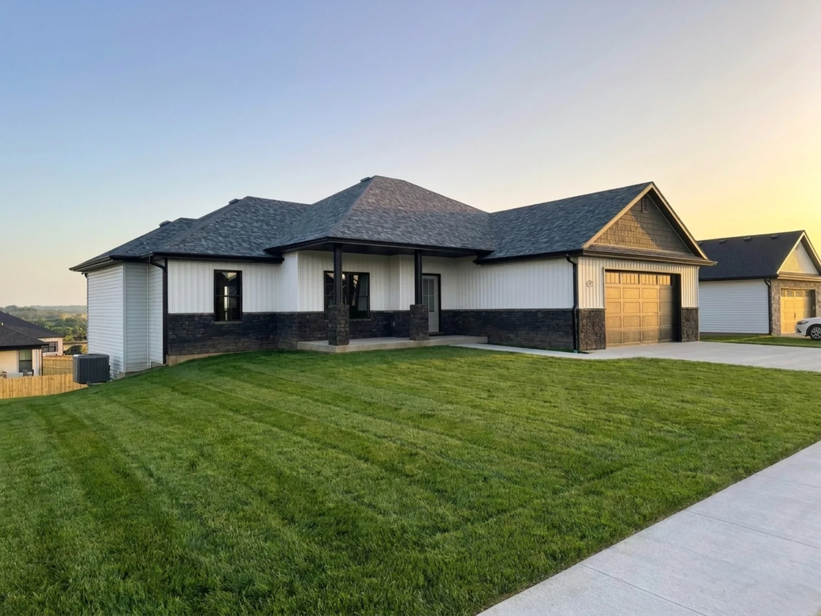 Nicholas property exterior with white siding, dark stone accents, a covered porch, attached garage and green lawn.